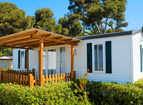 Dittmann Insurance_Personal & Commercial Insurance Southeast Kansas. Personal mobile/modular home insurance, a mobile home with a wooden trellis attached sits among a well-landscaped yard area.